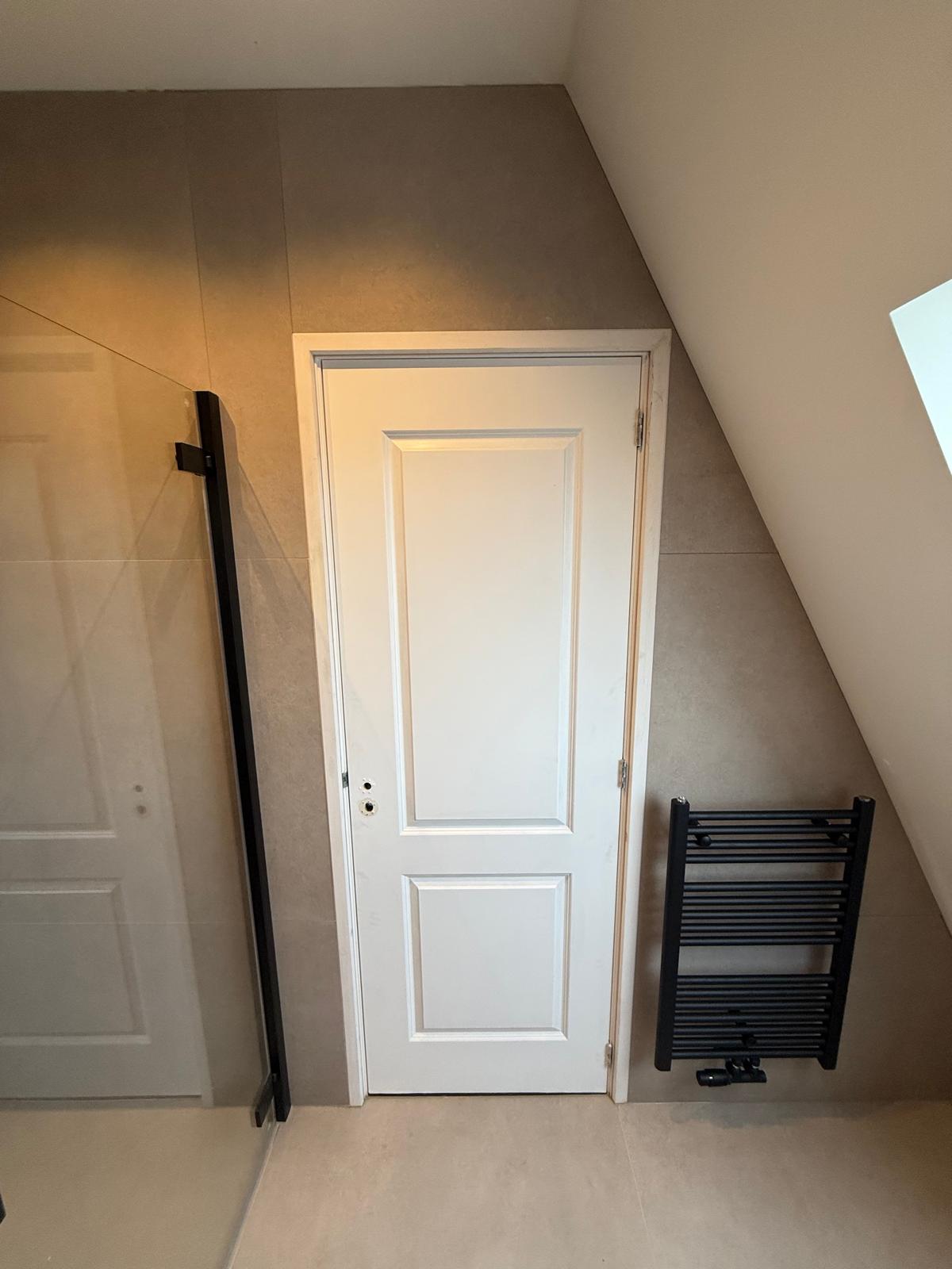 Inloopdouche met zwart kozijn naast handdoekradiator