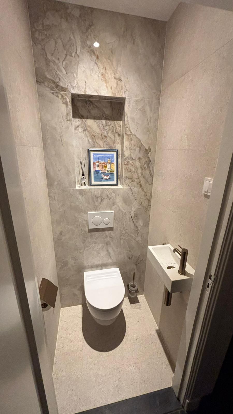 Gastentoilet met fonteintje en marmerlook tegelwerk