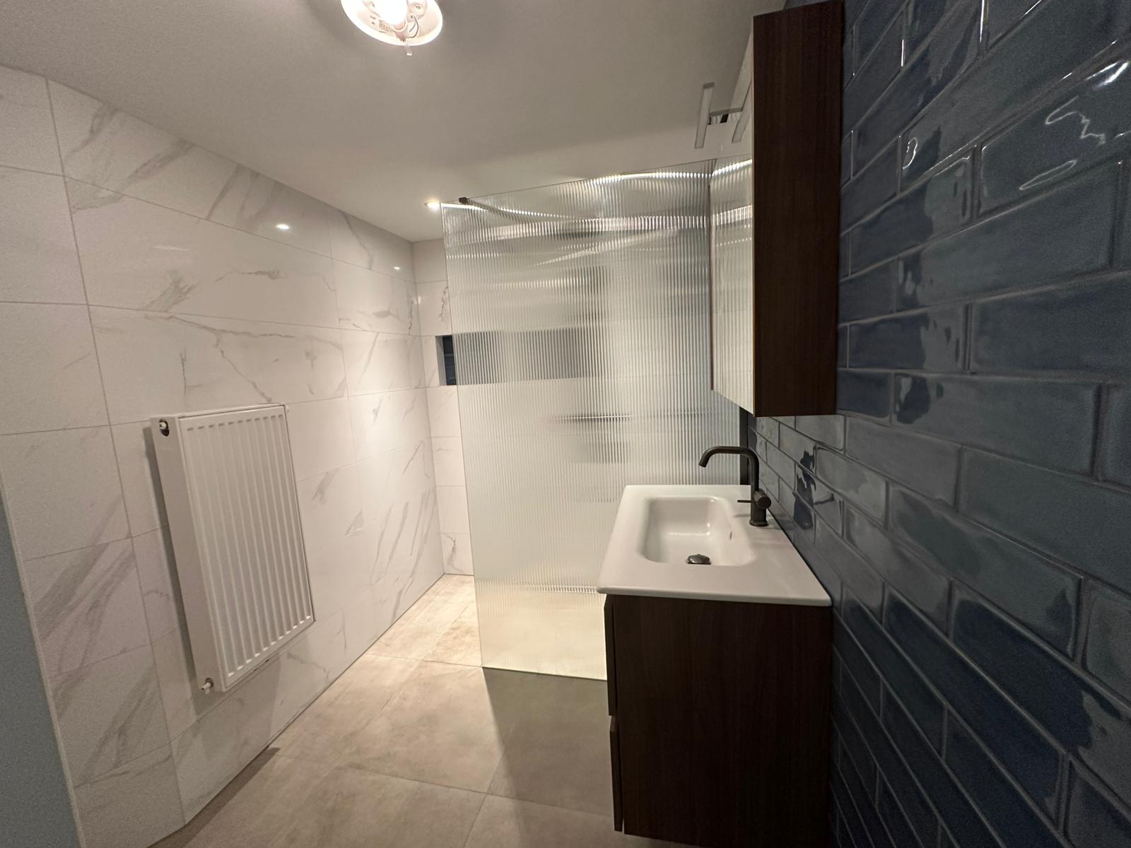 Vernieuwde badkamer met wit marmer, walnoot en marineblauw tegelwerk