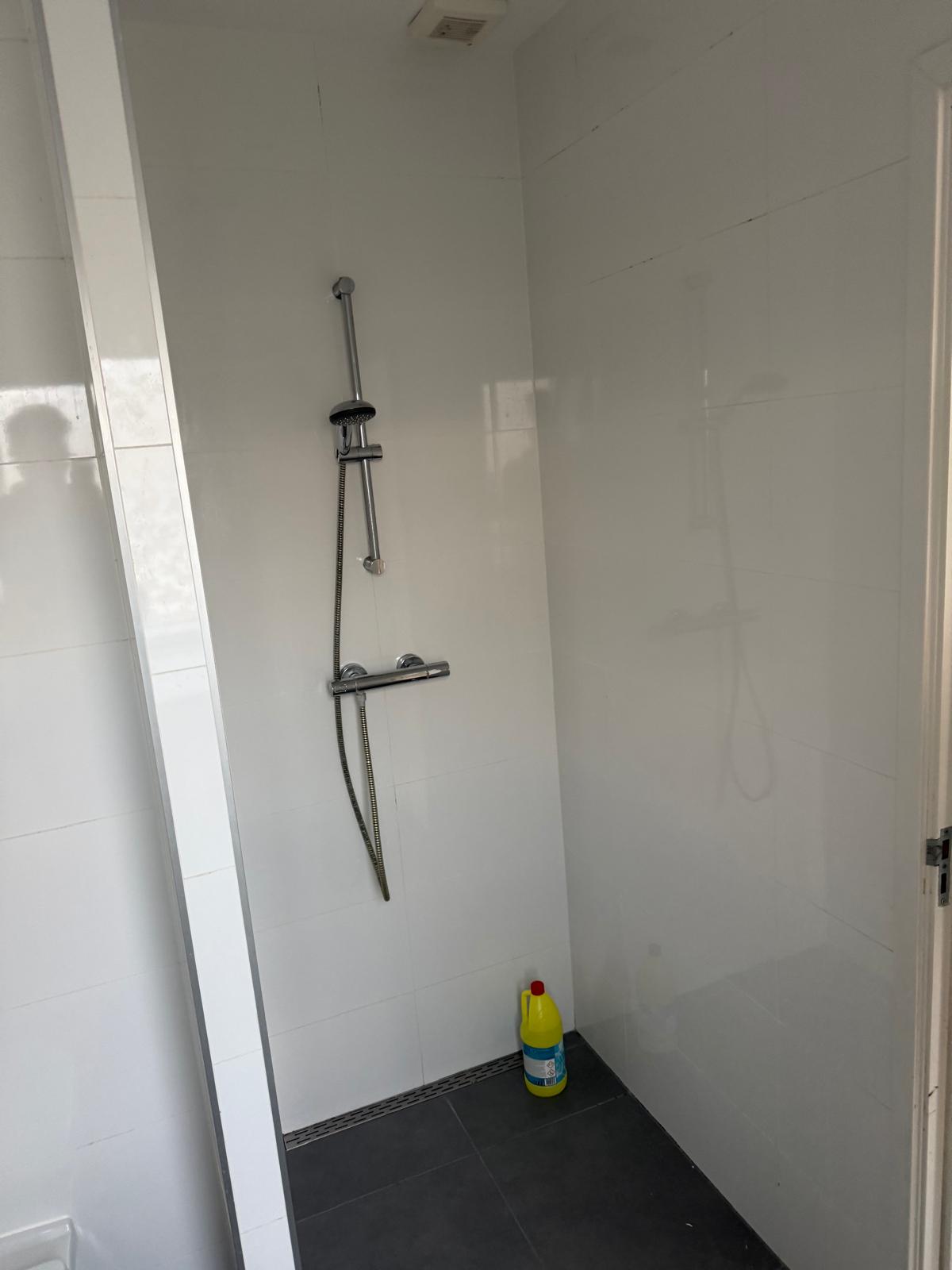 Verouderde badkamer met witte tegels, vóór renovatie