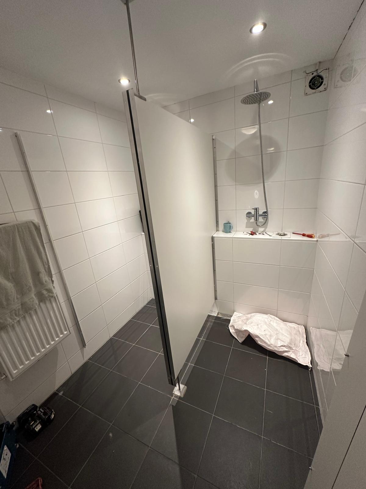 Verouderde douche met witte tegels, vóór renovatie